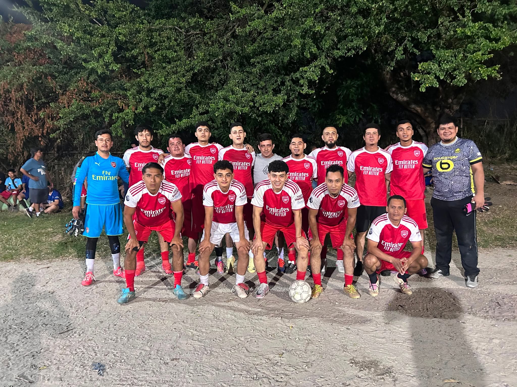 Equipo con uniforme rojo posando en una cancha de tierra